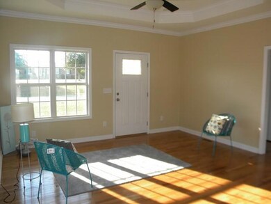 Large spacious living room with hardwood floors, natural light, and tray ceilings