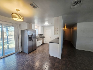 Kitchen featuring dark countertops, healthy amount of natural light, stainless steel appliances, and white cabinetry