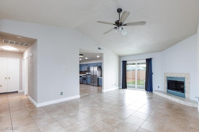 Unfurnished living room with a fireplace, vaulted ceiling, light tile patterned floors, and a ceiling fan
