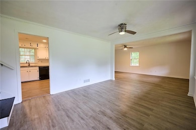 Empty room with a sink, wood finished floors, a ceiling fan, ornamental molding, and baseboards