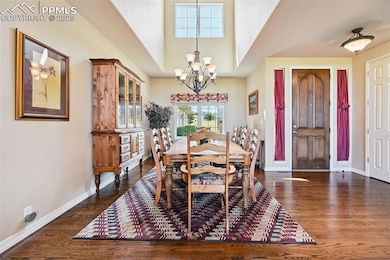 Dining space with a chandelier, wood finished floors, and a towering ceiling