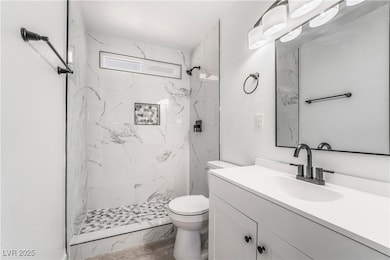 Full bath featuring a marble finish shower, toilet