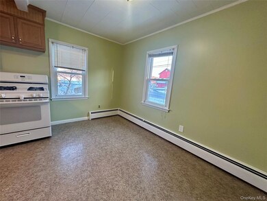 Kitchen with white gas range oven, a baseboard heating unit, and ornamental molding