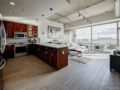 Kitchen with glass insert cabinets, stainless steel appliances, a peninsula, tasteful backsplash, and dark wood-style floors