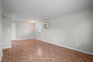 Unfurnished room with tile patterned flooring and an AC wall unit