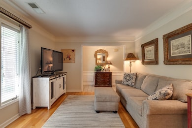 Living room with ornamental molding and light wood