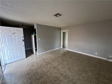Unfurnished room with a ceiling fan, a textured ce