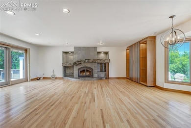 Unfurnished living room with a tiled fireplace, light wood-style flooring, recessed lighting, and a chandelier