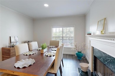 Dining area with a fireplace with flush hearth, wood finished floors, ornamental molding, and recessed lighting