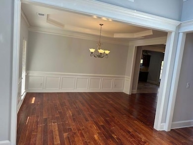 Unfurnished dining area featuring a chandelier, a decorative wall, a wainscoted wall, plenty of natural light, and dark wood finished floors