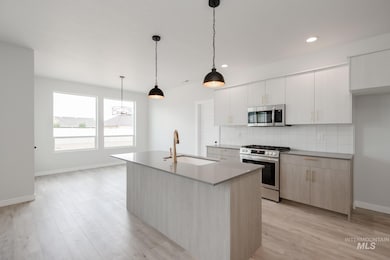 Kitchen with stainless steel appliances, backsplash, light wood-style floors, a center island with sink, and recessed lighting