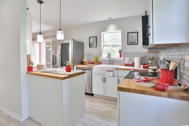 Kitchen featuring wooden counters, hanging light f
