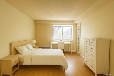 Bedroom featuring light wood-style floors, baseboard heating, and a textured ceiling