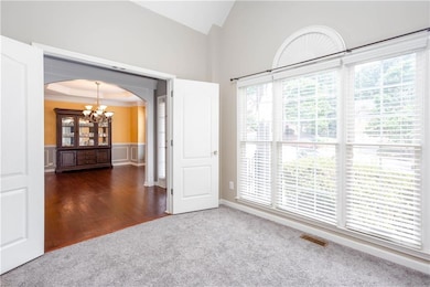 Carpeted empty room with ornamental molding, a chandelier, arched walkways, wainscoting, and wood finished floors