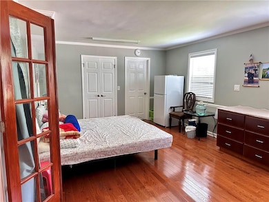 Bedroom featuring wood finished floors and crown molding