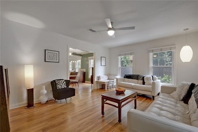 Living room with ceiling fan, light wood-type flo