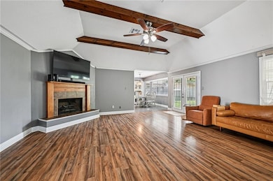 Open and inviting living room with vaulted ceilings, exposed wood beams, cozy fireplace, and abundant natural light.