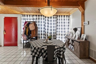 Dining area with wooden ceiling, light tile patterned floors, and a textured wall