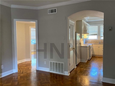 Unfurnished room featuring arched walkways and crown molding