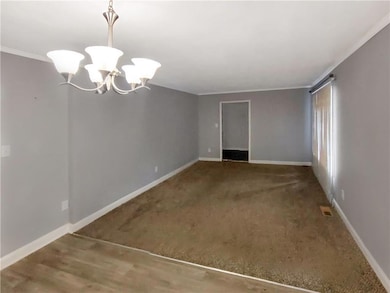 Spare room featuring a chandelier and crown molding