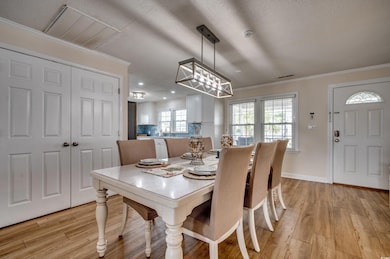 Dining area with light wood-style flooring, crown molding, a chandelier, recessed lighting, and a textured ceiling