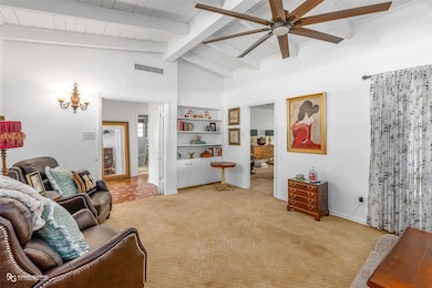 Living area featuring high vaulted ceiling, light carpet, ceiling fan, and beam ceiling