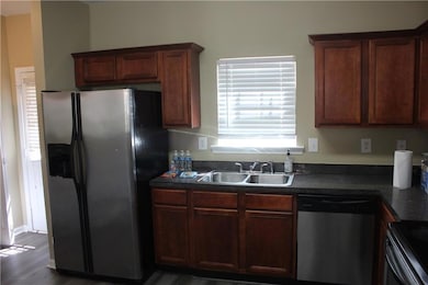 Kitchen with stainless steel appliances, dark countertops, and dark wood-type flooring