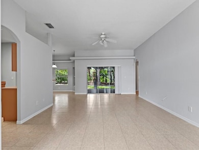 Unfurnished living room featuring arched walkways, light tile patterned floors, and a ceiling fan