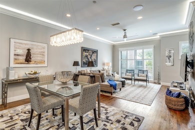 Dining area with illuminated crown molding, rich hardwood floors and recessed lighting throughout