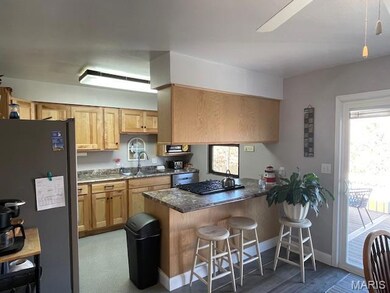 Kitchen with stainless steel appliances, a kitchen breakfast bar, a peninsula, dark stone counters, and a ceiling fan