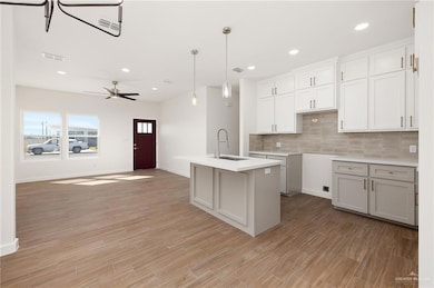 Kitchen featuring tasteful backsplash, pendant lighting, an island with sink, recessed lighting, and white cabinetry
