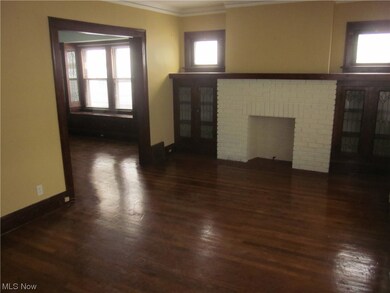 Unfurnished living room featuring dark wood-type flooring, a fireplace, and ornamental molding