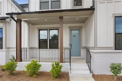 Doorway to property with board and batten siding, covered porch, and brick siding