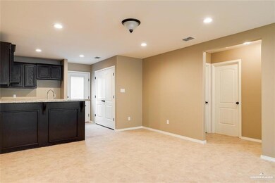 Kitchen with recessed lighting, baseboards, a sink, and dark cabinetry