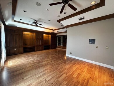 Unfurnished living room with ceiling fan, a tray ceiling, light wood-type flooring, and recessed lighting