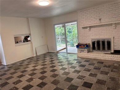 Unfurnished living room with a brick fireplace and baseboards