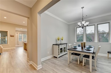 Dining space with ornamental molding, light wood-style floors, and a chandelier