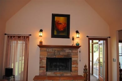 15 ft vaulted ceiling, custom stone fireplace surround, & hand rolled art glass light fixtures. French door leads to a fabulous screened porch!