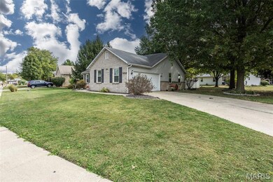 Ranch-style home featuring a front lawn, driveway, brick siding, and a garage