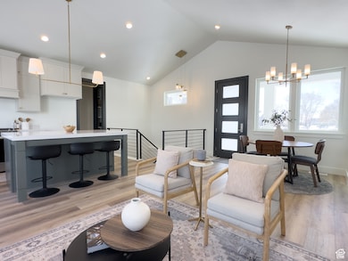 Living room featuring light wood-style flooring, a chandelier, recessed lighting, and high vaulted ceiling