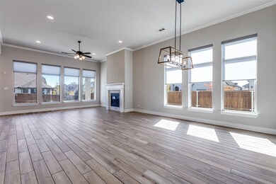 Unfurnished living room with crown molding, a tiled fireplace, a ceiling fan, a chandelier, and wood finished floors
