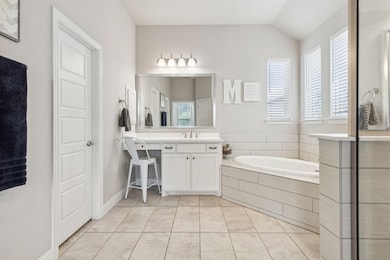 Bathroom featuring vanity, tiled bath, vaulted ceiling, and tile patterned floors