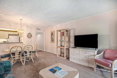 Carpeted living area featuring a chandelier, a textured ceiling, and ornamental molding