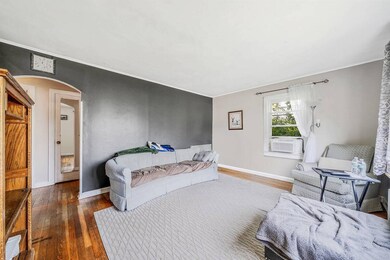 Bedroom featuring arched walkways, hardwood / wood-style flooring, cooling unit, and ornamental molding