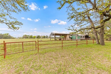 View of yard with a rural view, fence, a pole buil