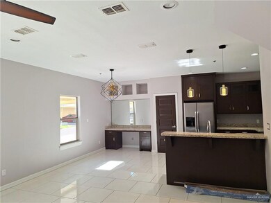 Kitchen with decorative light fixtures, dark brown cabinets, tasteful backsplash, stainless steel refrigerator with ice dispenser, and light tile patterned floors