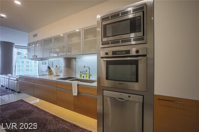 Kitchen with stainless steel appliances, glass insert cabinets, modern cabinets, brown cabinets, and white cabinetry