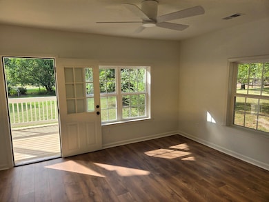 Unfurnished room with dark wood-type flooring and ceiling fan