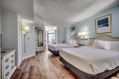 Bedroom with a textured ceiling, wood finished flo