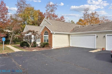 View of front of house featuring asphalt driveway, a shingled roof, brick siding, and an attached garage